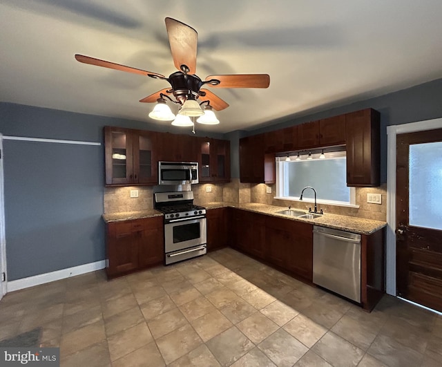 kitchen featuring light stone counters, stainless steel appliances, sink, and backsplash