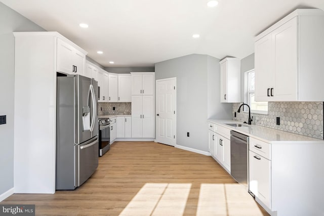 kitchen with sink, white cabinetry, light hardwood / wood-style flooring, appliances with stainless steel finishes, and decorative backsplash