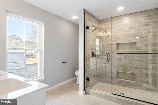 bathroom featuring vanity, a shower with door, and toilet