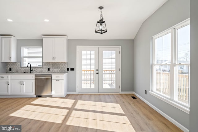 kitchen featuring white cabinetry, hanging light fixtures, stainless steel dishwasher, and sink