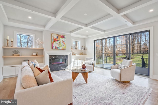 living room featuring coffered ceiling, a fireplace, beam ceiling, and light wood-type flooring