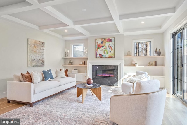 living room with coffered ceiling, beam ceiling, light hardwood / wood-style floors, and a premium fireplace