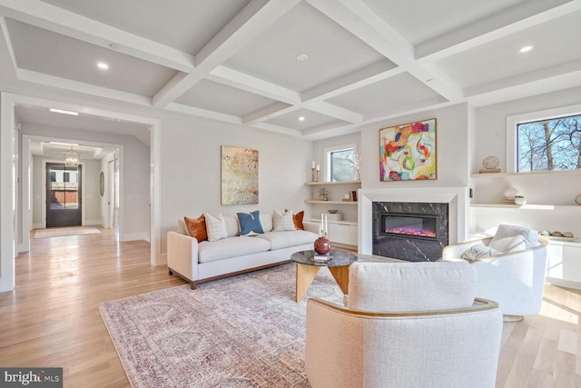 living room featuring coffered ceiling, beam ceiling, a fireplace, and light hardwood / wood-style floors