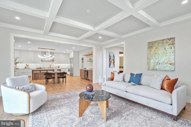 living room featuring beamed ceiling, coffered ceiling, light hardwood / wood-style flooring, and a notable chandelier