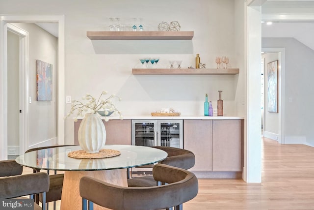 interior space featuring indoor bar, beverage cooler, and light hardwood / wood-style flooring