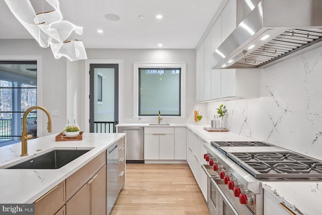 kitchen with white cabinetry, sink, hanging light fixtures, exhaust hood, and stainless steel appliances