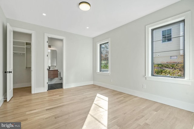 unfurnished bedroom with a spacious closet, light hardwood / wood-style floors, a closet, and ensuite bathroom