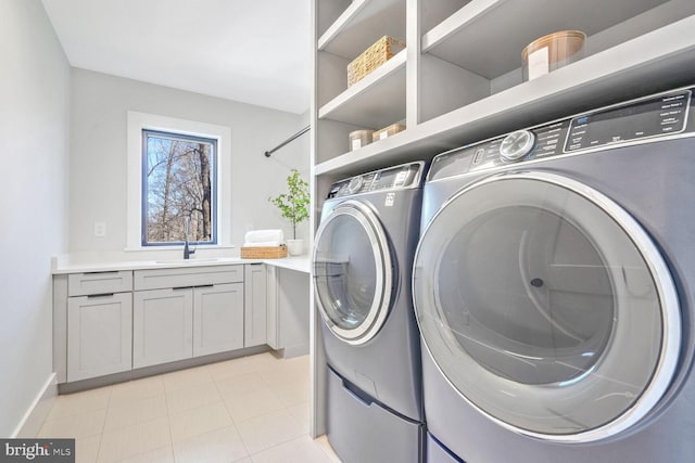 washroom with cabinets, sink, light tile patterned floors, and washer and clothes dryer