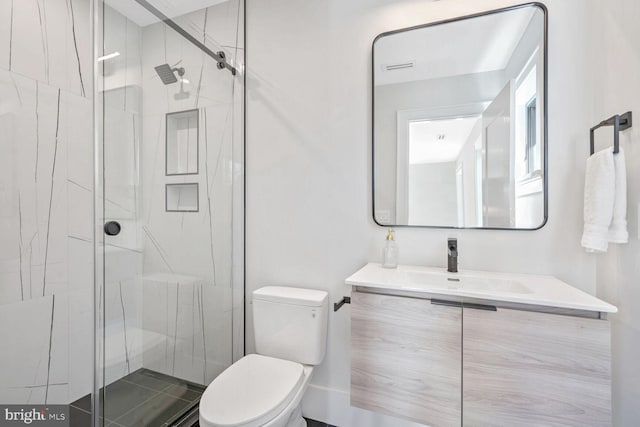 bathroom with vanity, a shower with door, and toilet