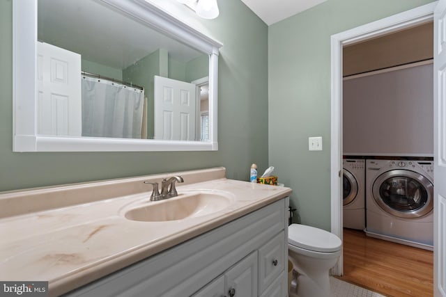 bathroom with vanity, hardwood / wood-style flooring, washing machine and dryer, and toilet