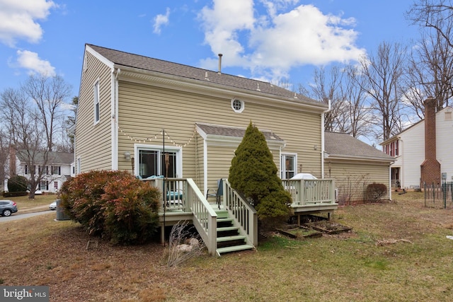 rear view of property featuring a yard and a deck