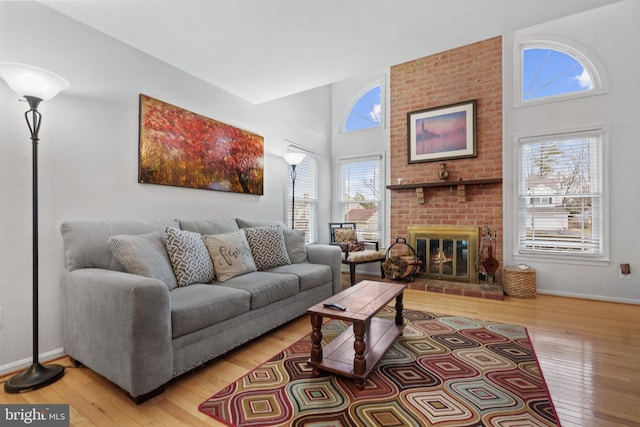 living room featuring hardwood / wood-style floors, a brick fireplace, and a high ceiling