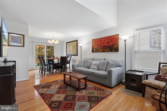 living room featuring a notable chandelier, a wood stove, and light wood-type flooring