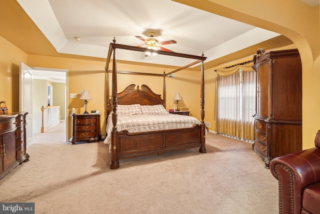 carpeted bedroom featuring a raised ceiling and ceiling fan