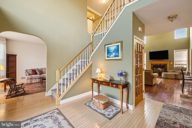 interior space featuring hardwood / wood-style flooring, ornamental molding, a premium fireplace, and a towering ceiling