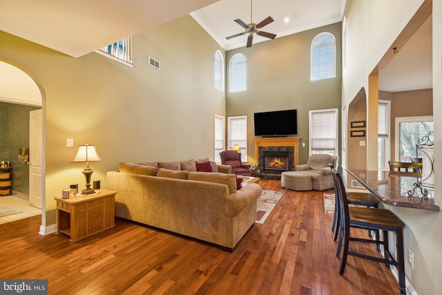 living room with ceiling fan, ornamental molding, a premium fireplace, and hardwood / wood-style floors