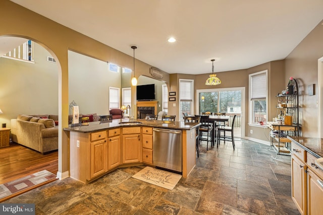 kitchen with sink, decorative light fixtures, dark stone countertops, light brown cabinets, and dishwasher