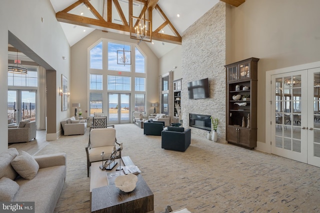 carpeted living room featuring a stone fireplace, an inviting chandelier, and french doors