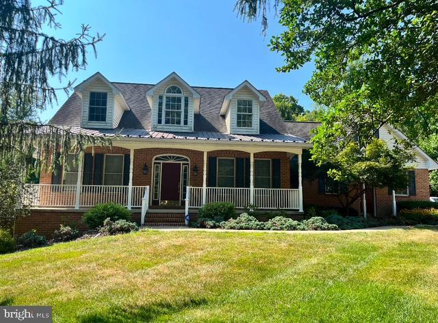 new england style home featuring covered porch and a front yard