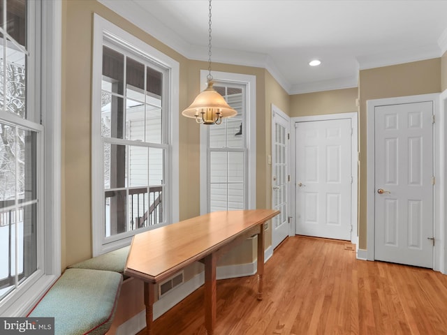 dining space with ornamental molding and light wood-type flooring