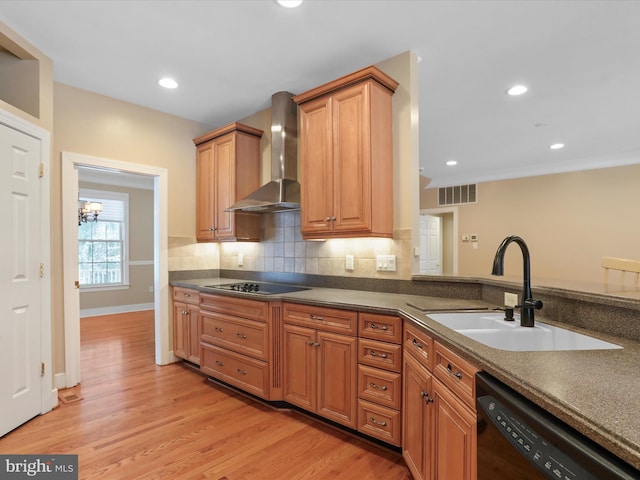 kitchen with wall chimney exhaust hood, sink, light wood-type flooring, decorative backsplash, and black appliances