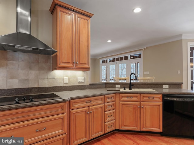 kitchen featuring black appliances, sink, dark stone counters, kitchen peninsula, and wall chimney range hood