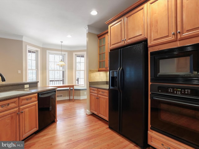 kitchen featuring pendant lighting, sink, ornamental molding, black appliances, and light hardwood / wood-style flooring