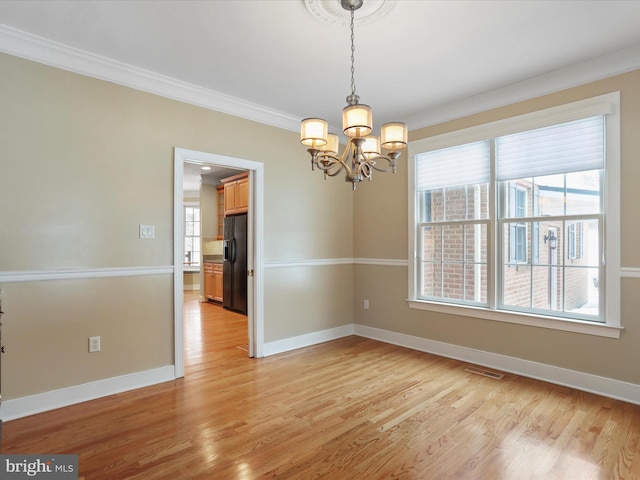 spare room featuring crown molding, a chandelier, and light wood-type flooring