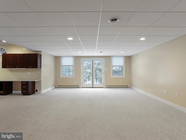 interior space featuring light carpet, built in desk, a baseboard radiator, and a drop ceiling