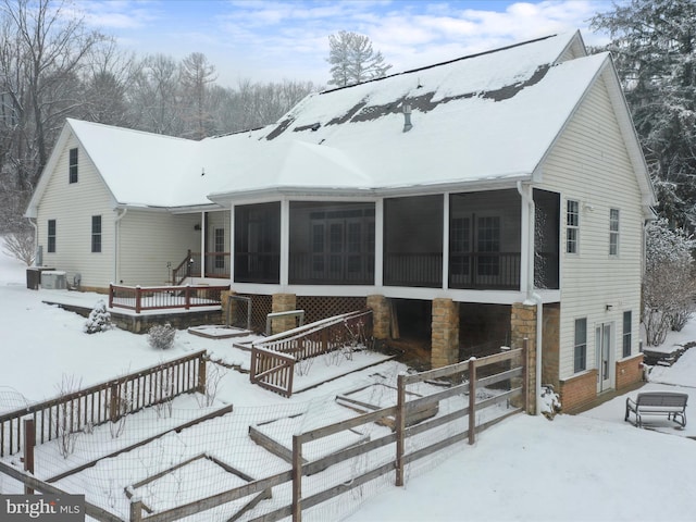 snow covered property featuring a sunroom and central AC