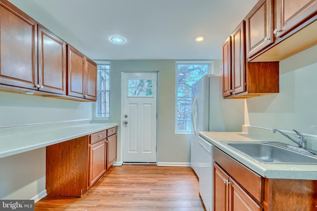 kitchen with sink, dishwasher, and light wood-type flooring