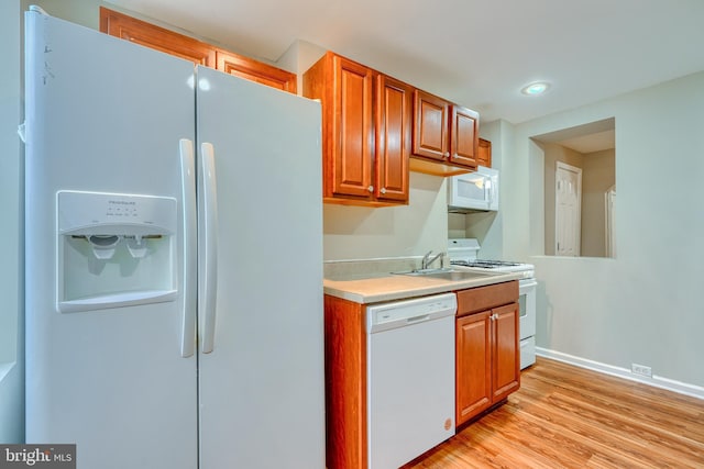 kitchen with white appliances, light hardwood / wood-style floors, and sink