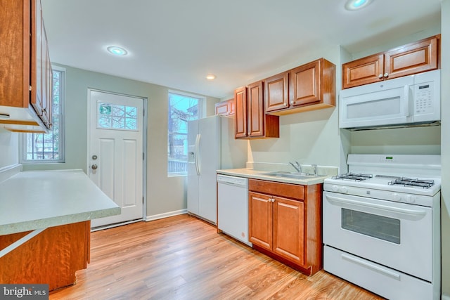 kitchen with plenty of natural light, sink, white appliances, and light hardwood / wood-style flooring