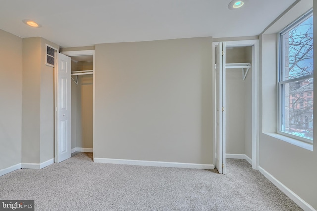 unfurnished bedroom with light carpet and two closets