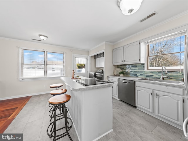 kitchen featuring washer and dryer, dishwasher, sink, white cabinets, and ornamental molding