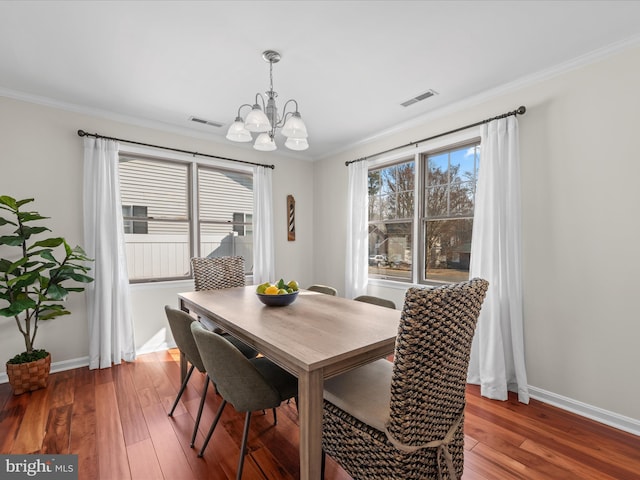 dining space featuring wood-type flooring, a notable chandelier, and crown molding