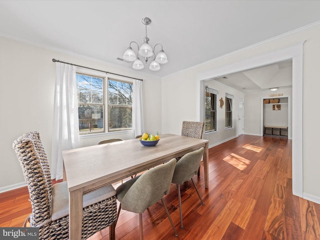 dining room with hardwood / wood-style flooring, ornamental molding, and a chandelier