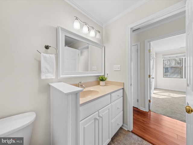 bathroom with hardwood / wood-style flooring, crown molding, vanity, and toilet