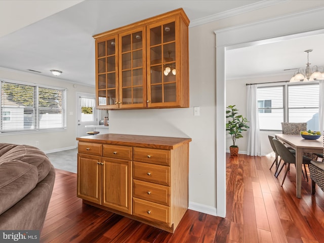 kitchen featuring crown molding, a chandelier, dark wood-type flooring, and pendant lighting