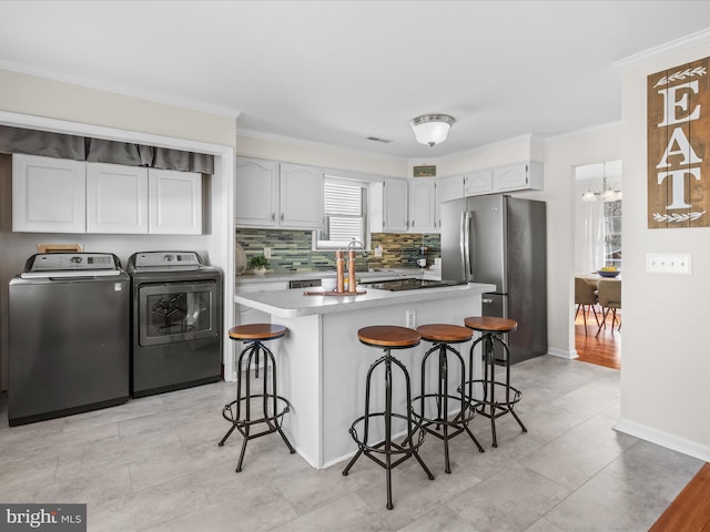 kitchen with stainless steel fridge, a kitchen breakfast bar, washer and dryer, white cabinets, and a kitchen island