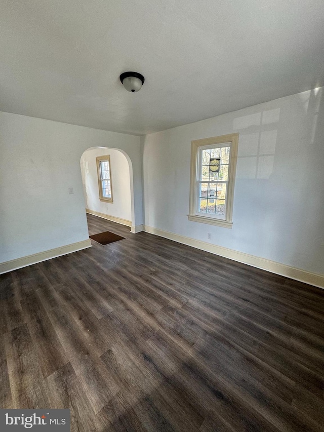 empty room featuring plenty of natural light and dark hardwood / wood-style floors