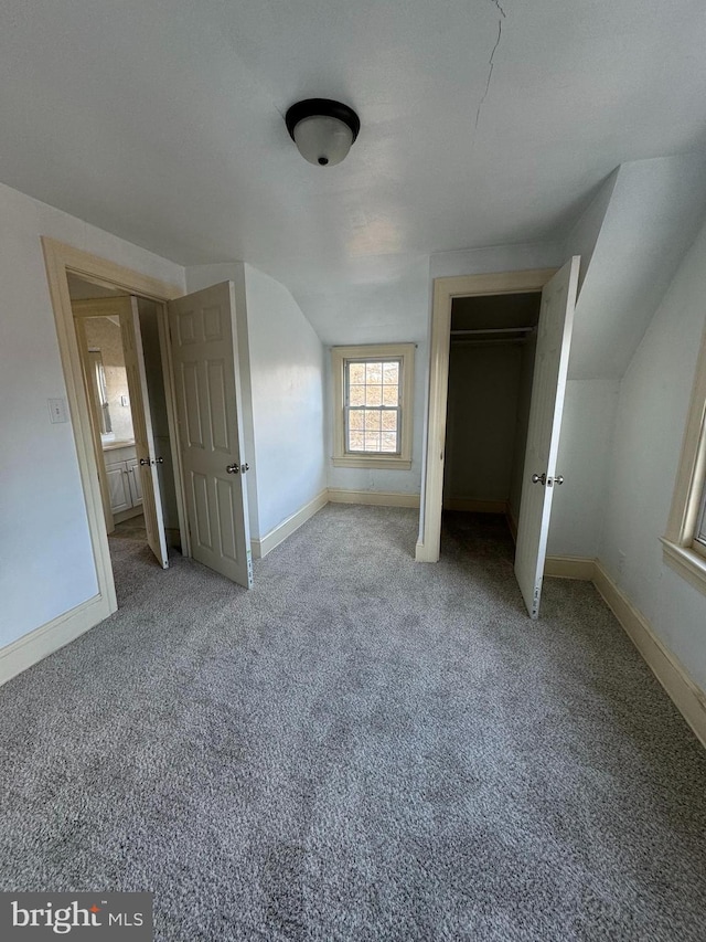 unfurnished bedroom featuring vaulted ceiling, a closet, and carpet flooring