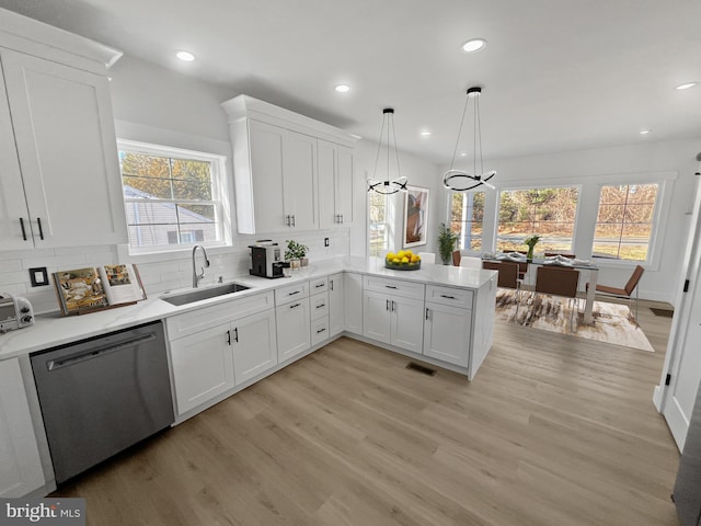 kitchen with sink, white cabinetry, decorative light fixtures, dishwasher, and kitchen peninsula