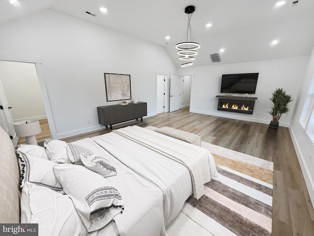 bedroom with an inviting chandelier, vaulted ceiling, and wood-type flooring