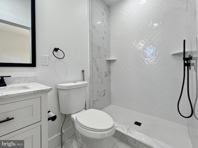 bathroom with a tile shower, vanity, and toilet