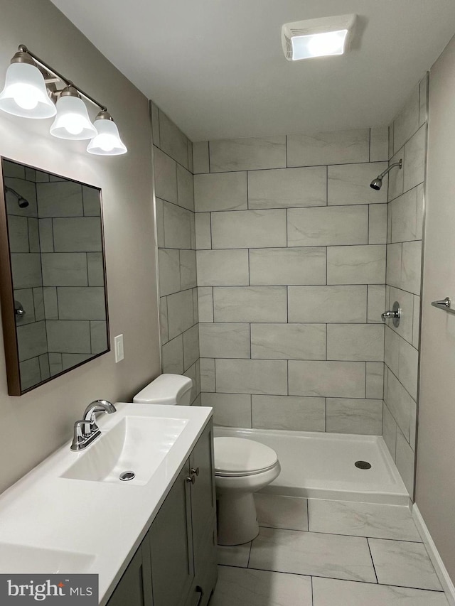 bathroom with vanity, a tile shower, and toilet