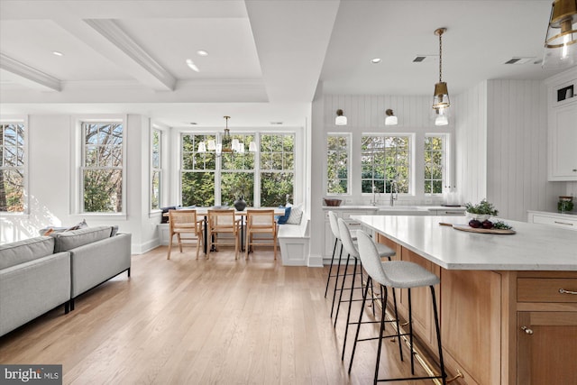 kitchen with decorative light fixtures, white cabinetry, a breakfast bar, and light wood-type flooring