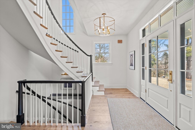 entryway with a chandelier, stairs, baseboards, and wood finished floors