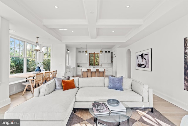 living room featuring beam ceiling, recessed lighting, light wood-style floors, arched walkways, and coffered ceiling