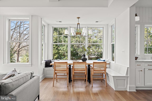 dining area with light wood-style flooring, a notable chandelier, visible vents, and breakfast area